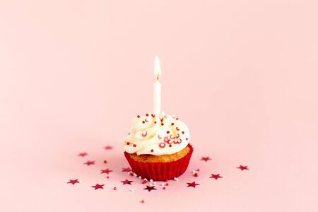 Birthday cupcake with buttercream icing and candle on pink pastel background. Place for text.の写真素材