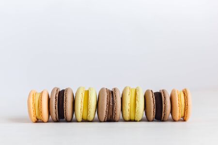 Set of French macarons on a white wooden table. Multicolored macarons. White background, pastel colors. Minimal concept, place for text.の写真素材