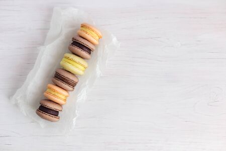 Set of French macarons on a white wooden table. Multicolored macarons. White background, pastel colors. Minimal concept, place for text. Flat lay.の写真素材