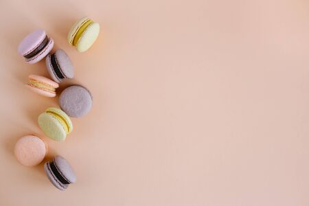 Tasty french macarons on a peach pastel background.  Place for text. Flat lay.