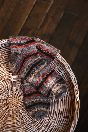 A pair of hand knitted multi-colored socks on a pad. Dark rustic wooden background. Plase for text.の写真素材