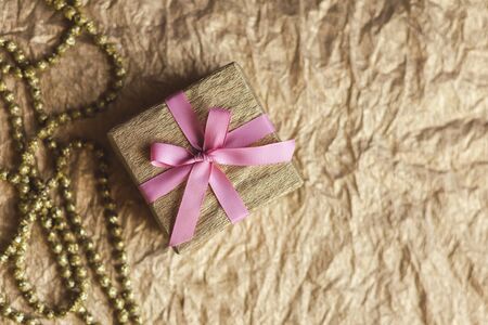 Golden gift box with pink bow on the gold background . Holiday concept. Flat lay. Place for text.の写真素材