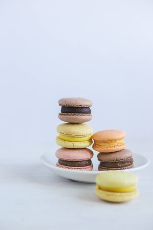 Tasty french macarons on a white plate.  White wooden background, pastel colors. Place for text.の写真素材