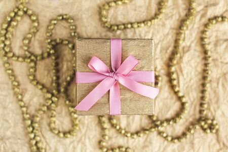 Golden gift box with pink bow on the gold background with decoration. Holiday concept. Flat lay.の写真素材