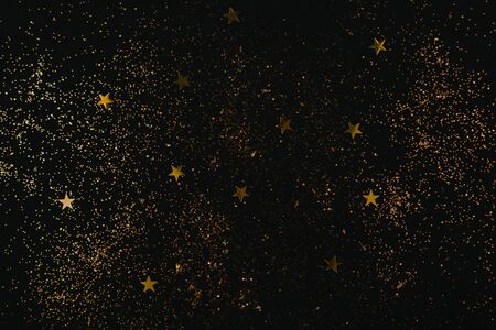 Golden sparkles and stars on black backdrop. Holiday concept. Flat lay.の写真素材
