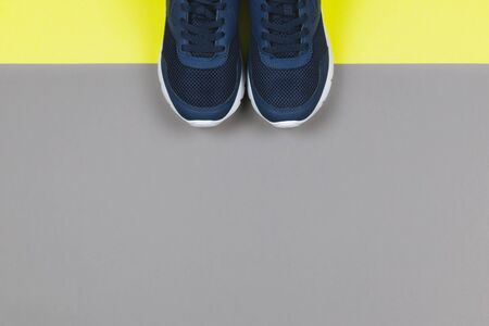 Classic blue sneakers on the yellow and grey background. Concept for healthy lifestyle and everyday training.  Place for text. の写真素材