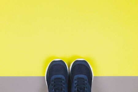 Classic blue sneakers on the yellow and grey background. Concept for healthy lifestyle and everyday training.  Place for text.の写真素材