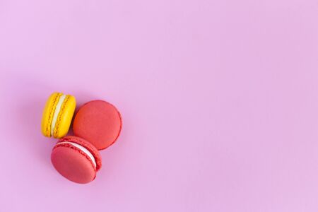 Three tasty french macarons on pink background. Pink and yellow macarons. Place for text. Flat lay.の写真素材