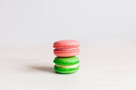 Tasty French macarons on a white wooden table. Pink and green macarons. White background. Minimal concept, place for text.の写真素材