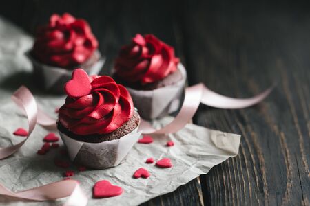 Valentine cupcakes in red color, decorated with sweet hearts on dark wooden table. Place for text.の写真素材