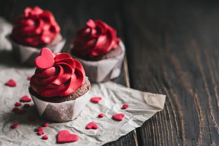 Valentine cupcakes in red color, decorated with sweet hearts on dark wooden table. Place for text.の写真素材