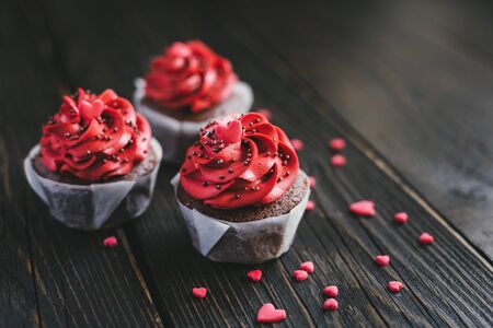 Valentine cupcakes in red color, decorated with sweet hearts on dark wooden table. Place for text.の写真素材