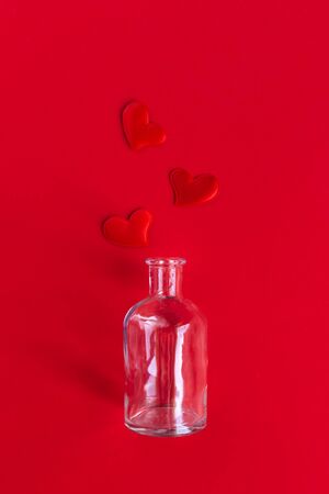 Bottle with red hearts on red background. Minimal concept for Valentine day. Falt lay.の写真素材