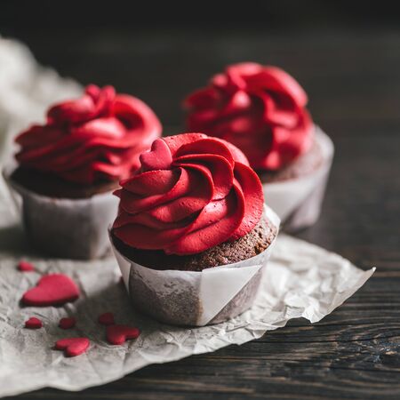 Valentine cupcakes in red color, decorated with sweet hearts on dark wooden table. Place for text.の写真素材