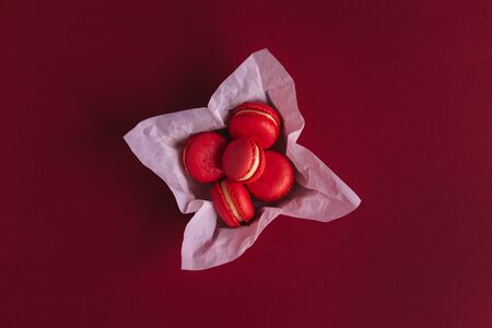 Red french macarons in a box on a dark red background. Concept for Valentine's day. Place for text. Flat lay.の写真素材