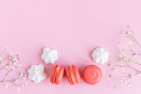 Pink macarons, white marshmallows and flowers on a pink pastel background. Flat lay, place for text.の写真素材
