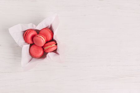 Red french macarons in a box on a white wooden background. Concept for Valentine's day. Place for text. Flat lay.の写真素材
