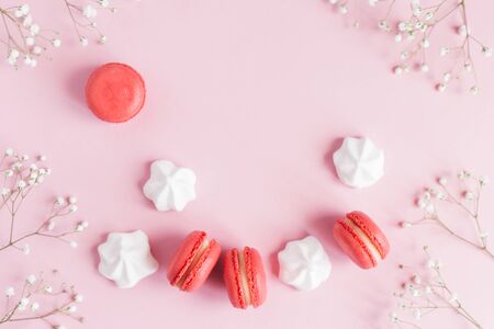 Pink macarons, white marshmallows and flowers on a pink pastel background. Flat lay, place for text.の写真素材