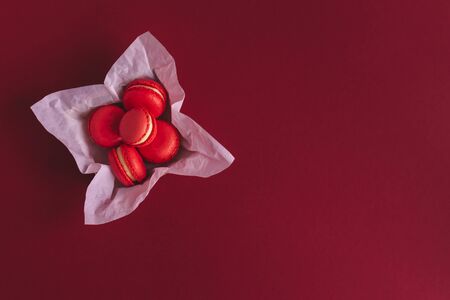 Red french macarons in a box on a dark red background. Place for text. Flat lay.の写真素材