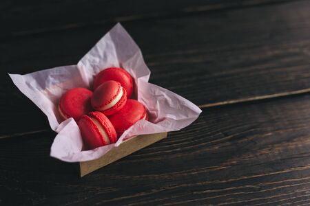 Red french macarons in a box on dark wooden table. Place for text.の写真素材