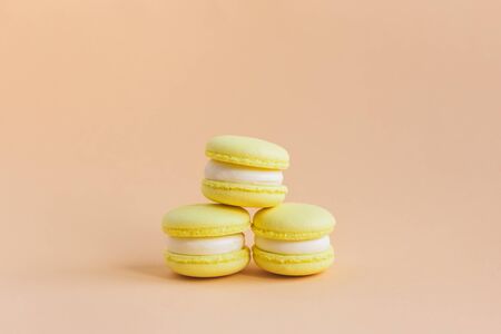 Yellow macarons on a peach pastel background. Lemon macarons. Place for text.の写真素材