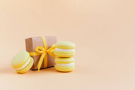 Yellow macarons with gift box on a peach pastel background. Lemon macarons. Place for text.の写真素材