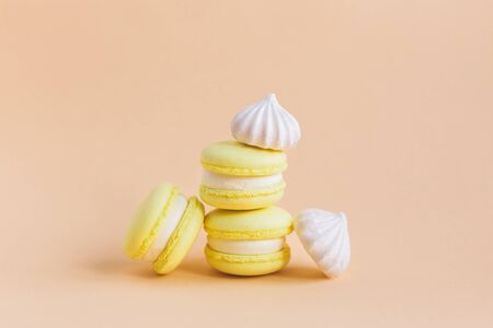 Yellow macarons and white marshmallows on a peach pastel background. Place for text.の写真素材