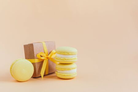Yellow macarons with gift box on a peach pastel background. Lemon macarons. Place for text.の写真素材