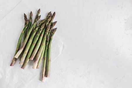 Bunch of asparagus in a white paper on white background. Flat lay. Place for text.の写真素材