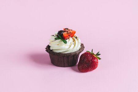 Tasty cupcake, decorated with fresh strawberry on pink pastel background. Place for text.の写真素材