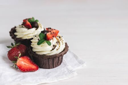 Tasty cupcake, decorated with fresh strawberry on white wooden background. Place for text.の写真素材