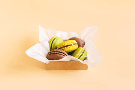 Tasty french macarons in a box on a peach pastel background. Place for text.