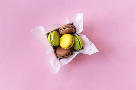Tasty french macarons in a box on pink pastel background. Place for text. Flat lay.