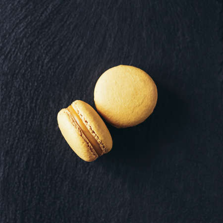 Yellow french macarons on a black background. Minimal concept. Flat lay, place for text.の写真素材
