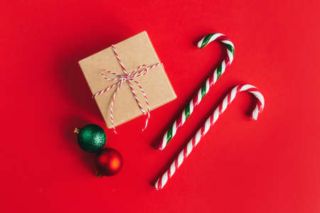 Gift box with balls and candy canes on a red background. Place for text. Flat lay.の写真素材