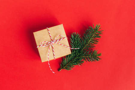 Craft box with spruce branch on a red background. Minimal concept. Place for text. Flat lay.の写真素材