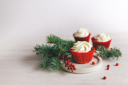 Tasty cupcakes decorated with spruce branches and red berries on a white wooden background. Sweets for the celebration Christmas. Holiday eco-friendly concept. Place for text.の写真素材