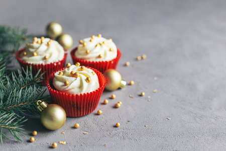 Tasty cupcakes decorated with golden pearls and spruce branches on a gray background. Sweets for the celebration Christmas. Place for text.の写真素材