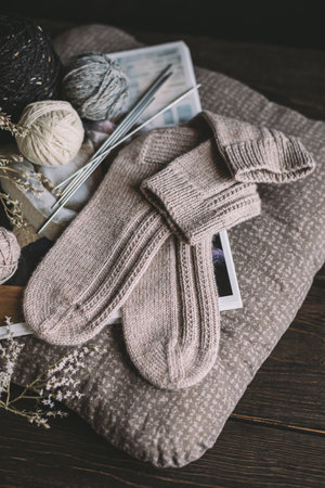 A pair of hand knitted socks with yarn balls. Natural colors. Dark rustic wooden background.