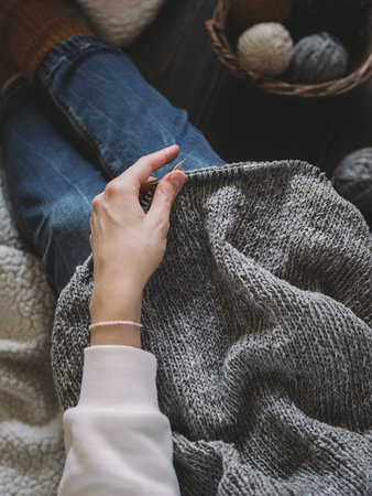 Woman with hand knitting, needles and yarn balls in a basket on a dark background. Concept for handmade and hygge slow life.の写真素材
