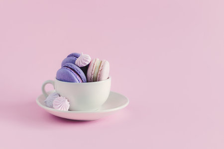 Cup with french macarons and marshmallows on a pink pastel background. Place for text.の写真素材