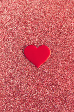 Red heart on a red sparkle background. Minimal concept for Valentine day. Falt lay.の写真素材