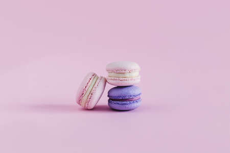 Tasty french macarons on a pink pastel background. Pink and violet macarons. Place for text.