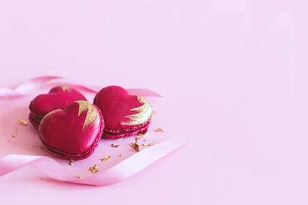 Heart-shaped macaroons with ribbon on a pink pastel background. Concept for Valentine's Day. Place...