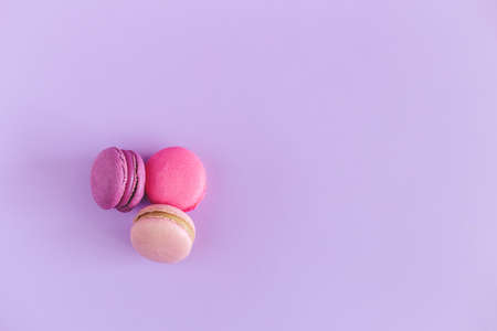 Tasty french macarons on a violet pastel background. Pink and violet macarons. Place for text.