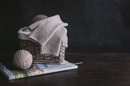 Hand knitted mittens with needles and yarn balls ion a dark wooden background. Concept for handmade and hygge slow life. Place for text.の写真素材
