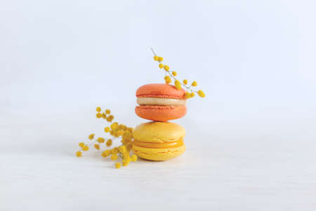Tasty french macaroons with flowers on a white wooden background. Yellow colors. Place for text.の写真素材