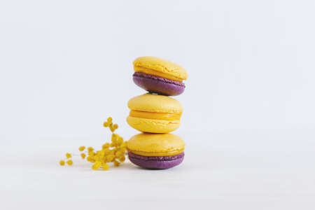 Tasty french macaroons with flowers on a white wooden background. Violet and yellow colors. Place for text.の写真素材