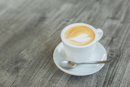 Cup of coffee with latte art on rustic wooden table. Place for text.の写真素材