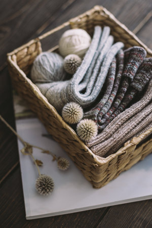 Hand knitting socks with yarn balls in a basket on a dark wooden background. Concept for handmade...